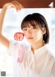 A woman in a white shirt holding a pink heart.