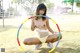 A young woman is playing with a hula hoop in the grass.