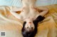A naked woman laying on a bed with her hands on her breasts.