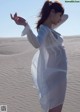 A woman in a white dress standing in the sand.